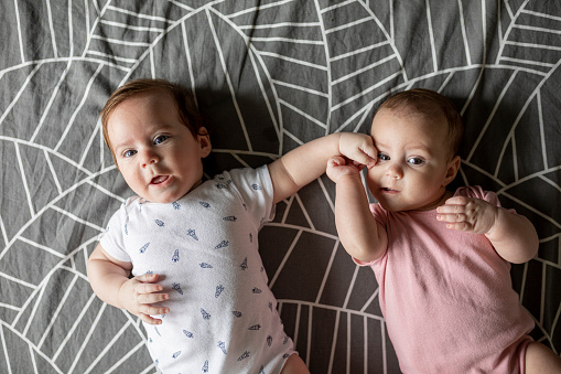 Cute twin boy and girl babies portrait lying on bed