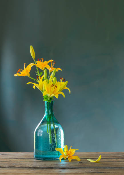 istock yellow lilies in glass vase on dark background 1469962119