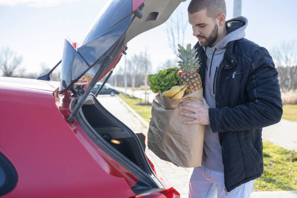 istock Young man putting groceries in his car 1469962550