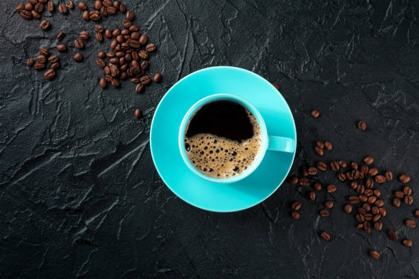 Coffee cup, shot from the top on a black slate background with coffee beans