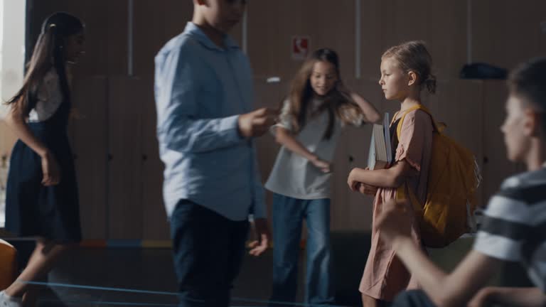 Tensed schoolgirl walking hall full students. Girl holding books going on break.