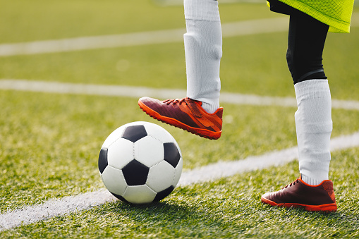 Youth Football Background. Young Boy Wearing Soccer Cleats, Socks and Soccer Pants. Kid Kicking Classic Soccer Ball
