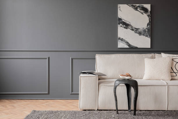 istock Minimalist composition of living room interior with mock up poster frame,  copy space, modular sofa, wooden coffee table, carpet, dark wall with stucco and personal accessories. Home decor. Template. 1469964069