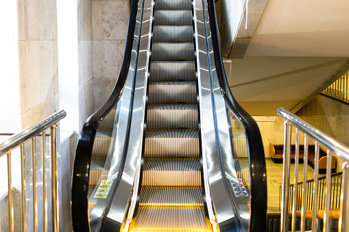 front view of indoor moving escalator with yellow electric backlight
