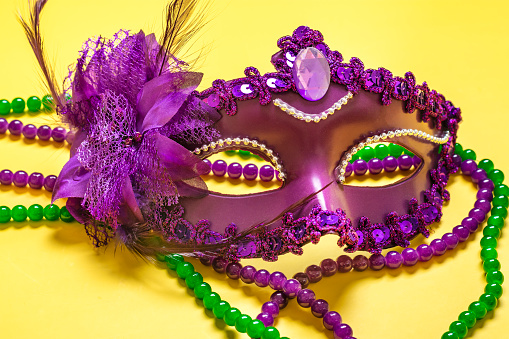Mardi gras concept. Congratulation card with violet mask on yellow background Top view 2023 Mardi Gras Parade Schedule Mockup Copy space.