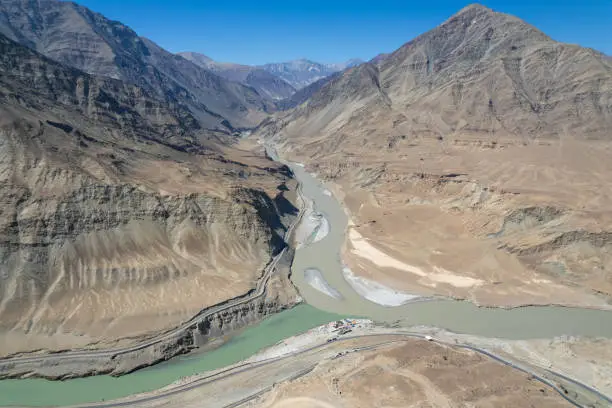 Aerial view of Sangam – the confluence of the Indus river (green colour) and the Zanskar river (blue or brown colour depending on the season) in Ladakh, India.