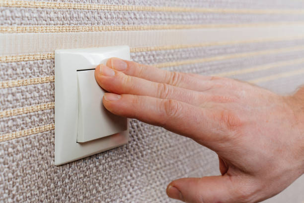 istock men's hand on White light switch on the wall with brown wallpaper. 1469971131
