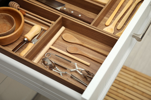 Open drawer of kitchen cabinet with different utensils, closeup