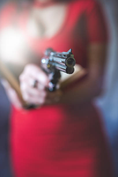 female spy agent with a gun in her hand on grey. crime concept