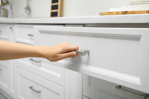 Woman opening drawer in kitchen, closeup view