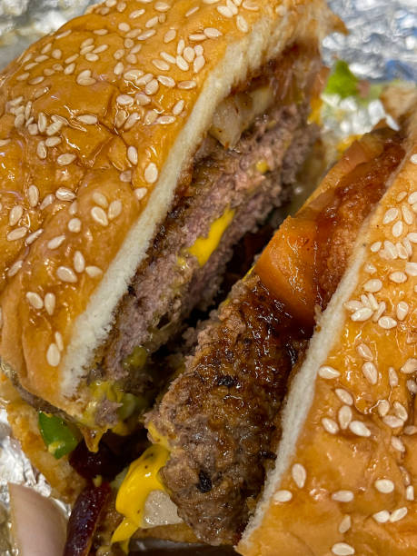 istock Full frame image of gourmet bacon cheeseburger on aluminium foil, melted cheese slice, fast food beef hamburger patty, bacon rashers, onion relish, lettuce, gourmet burger bar takeaway restaurant, elevated view 1469975341