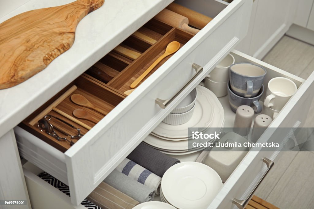 Open drawers of kitchen cabinet with different dishware, utensils and towels Kitchen Stock Photo