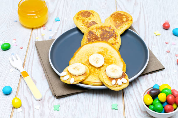Easter funny creative healthy breakfast lunch food idea for kids, children.Bunny, rabbit made from pancakes,banana with honey,sweet candies,eggs on plate wooden table background.Top view Flat lay Easter funny creative healthy breakfast lunch food idea for kids, children.Bunny, rabbit made from pancakes,banana with honey,sweet candies,eggs on plate wooden table background.Top view Flat lay. bunny pancake stock pictures, royalty-free photos & images