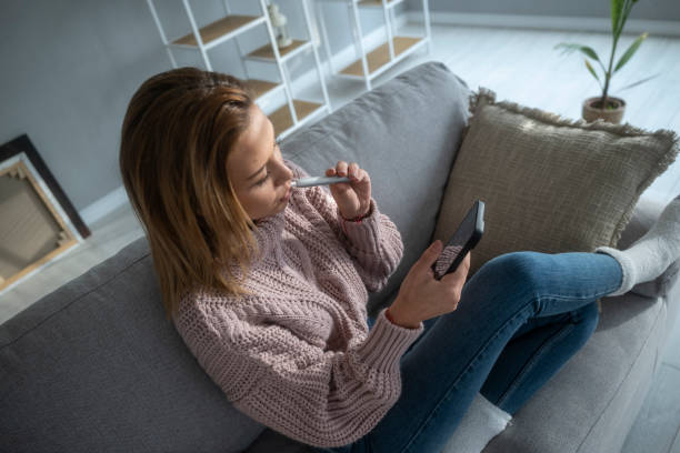 istock Girl relaxes at home with phone and e-cigarette. Vaping. 1469978250