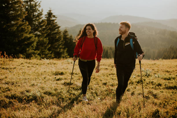 istock Smiling couple walking with backpacks over green hills 1469978648