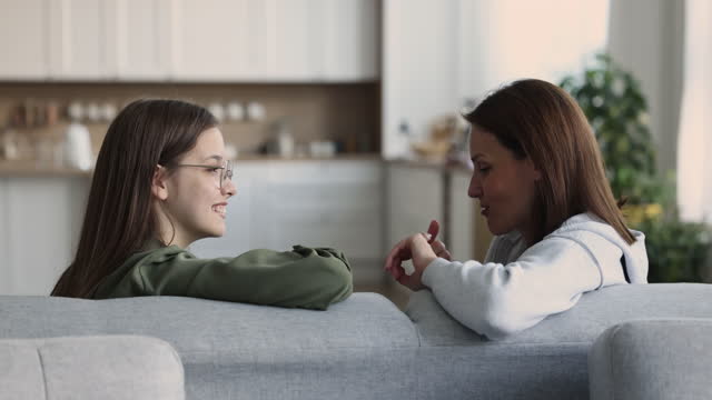 Attractive mom talks to teenage daughter at home