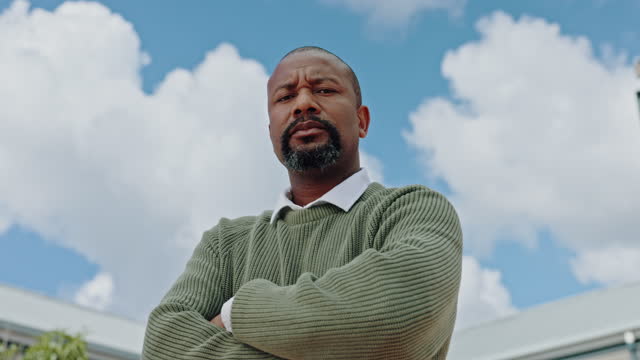 Power, serious and face of a black man with arms crossed on a blue sky in the city of Morocco. Vision, success and portrait of an African businessman with arms folded for executive confidence