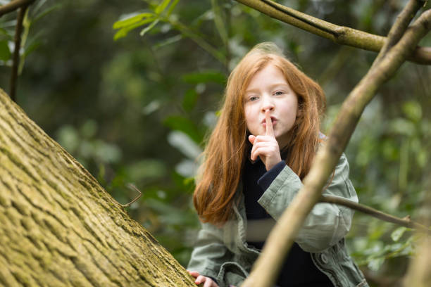 Redhead aged 8 playing hide and seek in the woods.