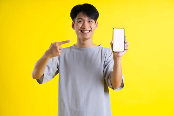 istock image of a handsome young man using his phone and posing on a yellow background 1469981744