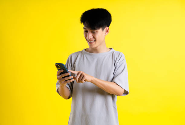 istock image of a handsome young man using his phone and posing on a yellow background 1469981761