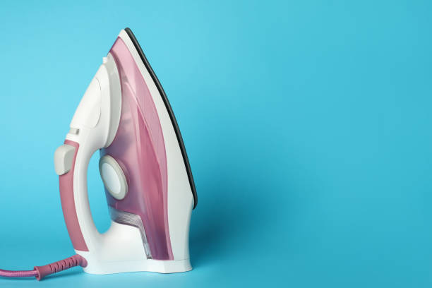 istock One modern iron on light blue background, space for text. Home appliance 1469981882