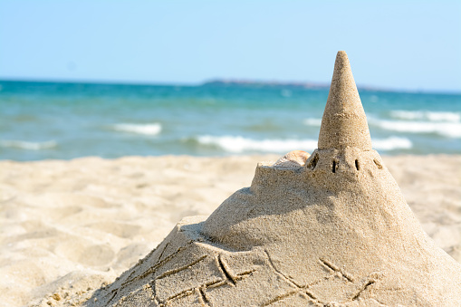 Beach with sand castle near sea on sunny day. Space for text