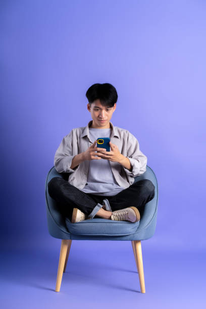 istock full body image of young asian man using phone on purple background 1469982228