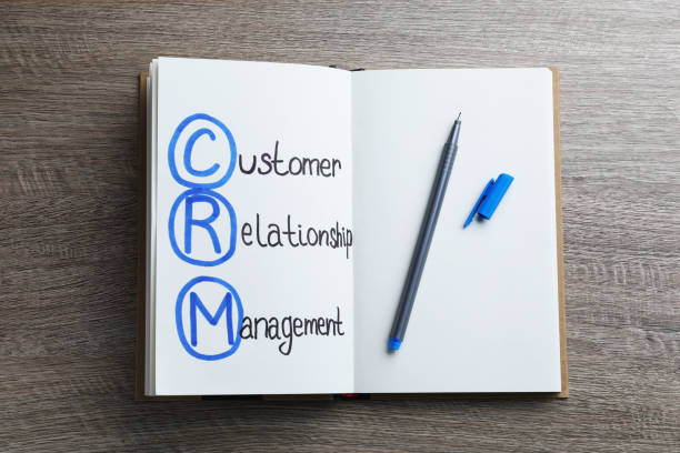istock Notebook with abbreviation CRM (Customer Relationship Management) and pen on wooden background, top view 1469982426
