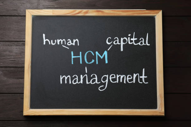 istock Small blackboard with abbreviation HCM (Human Capital Management) on wooden background, top view 1469982438