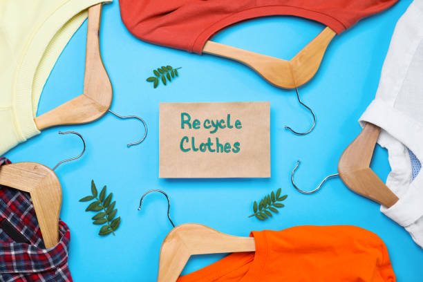 istock Different clothes with recycling label and hangers on light blue background, flat lay 1469982719