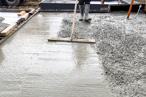 Worker builder smoothing concrete of a slab at a construction site