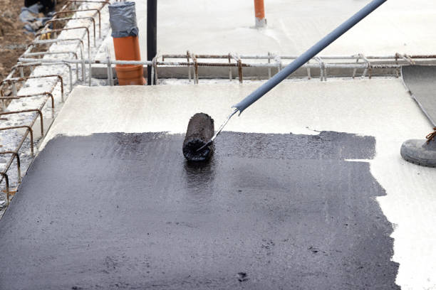 Worker applying a bituminous primer on a Concrete Slab Before Waterproofing stock photo