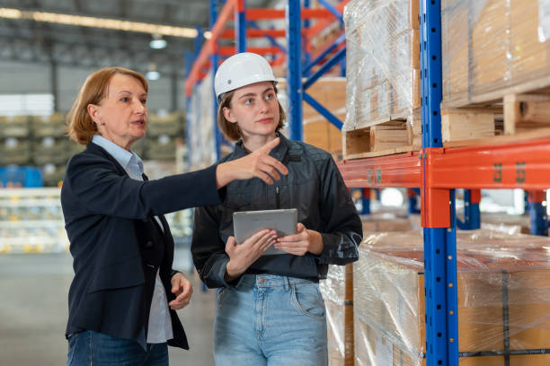 istock Teamwork engagement can increase productivity and efficiency in warehouse operations. Engineer worker holding tablet and discuss with senior Caucasian warehouse manager in the distributor warehouse factory. 1469983833