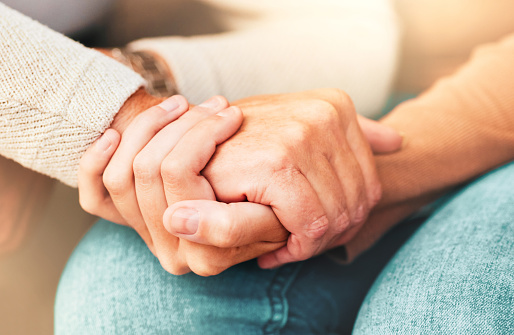 Closeup of a support hands. Closeup shot of a young woman holding a senior man's hands in comfort. Female carer holding hands of senior man