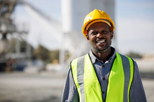 ritratto di ingegnere sorridente con il cappello rigido in cantiere - manufacturing occupation african descent refinery manual worker foto e immagini stock