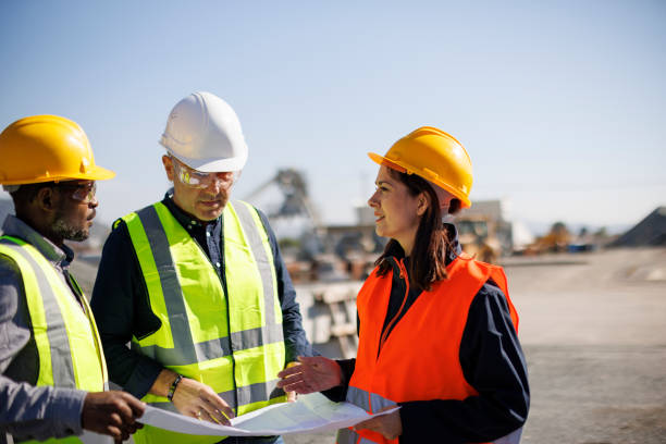 Engineers and architect discussing building plan at construction site stock photo