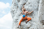 Athletic woman climbing on cliff rock