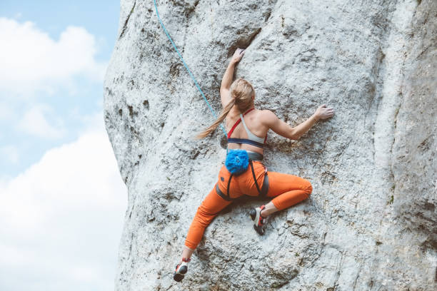 Athletic woman climbing on cliff rock stock photo