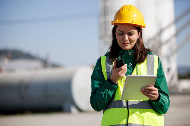 産業施設でトランシーバーとデジタルタブレットを使用する女性エンジニアのポートレート - oil industry digital tablet manual worker mining ストックフォトと画像