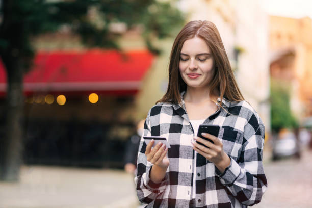 istock Cheerful young beautiful woman using smartphone and credit card 1469988580