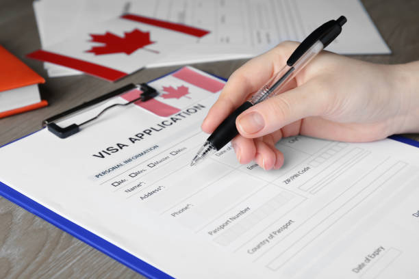 istock Woman filling visa application form to Canada at table, closeup 1469991568