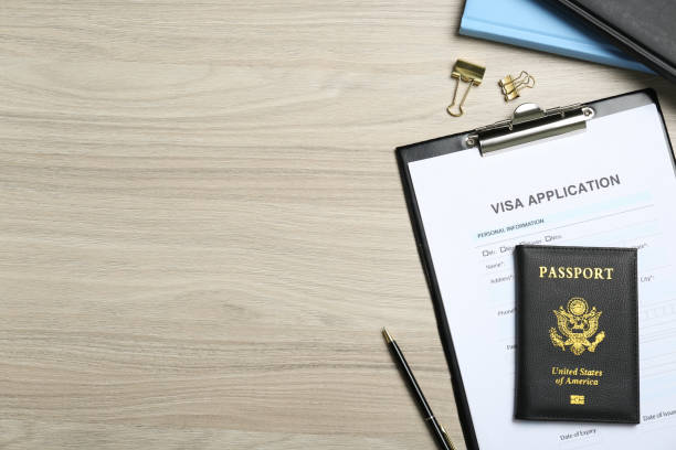 istock Visa application form, passport and stationery on wooden table, flat lay. Space for text 1469991761