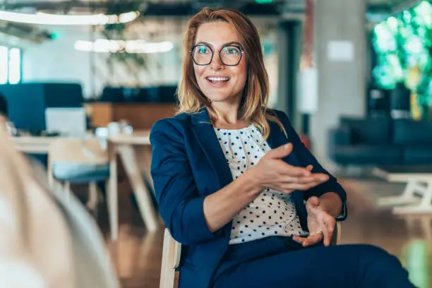 Middle aged businesswoman in a conversation with a colleague. Lawyer consulting client during formal meeting. Job interview and hiring process. Diverse colleagues discussing project concept