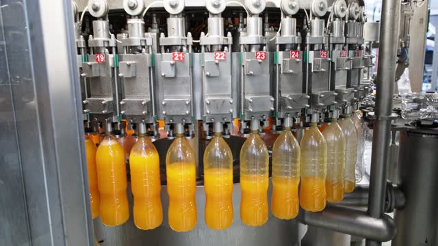 Machine filling plastic bottles with juice at the beverage factory
