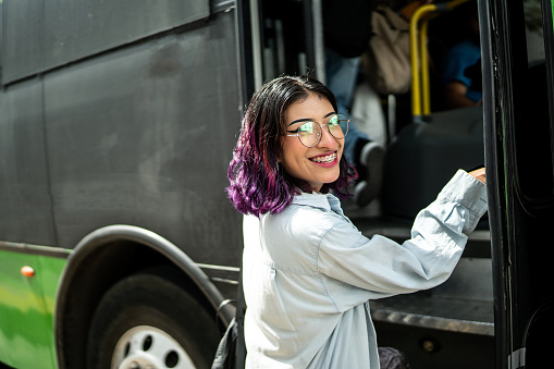 Portrait of young woman getting on the bus