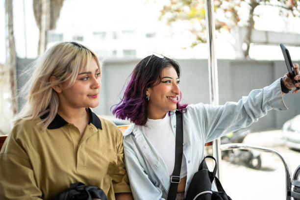 istock Young women taking a selfie using mobile phone on a open-air bus 1469992383