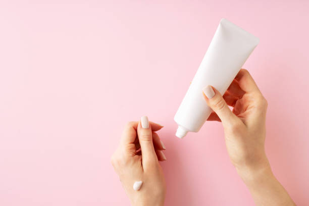 istock Womans hands with cream on pink background 1469992436