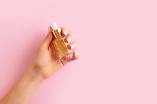 istock Womans hands with serum on pink background 1469992445