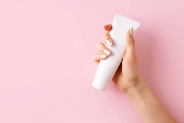 istock Womans hands with cream on pink background 1469992460