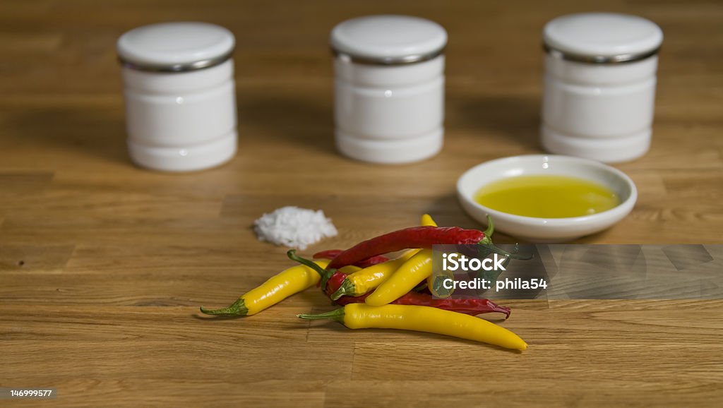 Chilli Red and white chili on a stylish oak table with olive oil and salt, and small white spice racks out of focus Extra Virgin Olive Oil Stock Photo